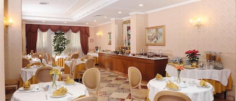 A dining area with round tables, chairs, and a buffet station.