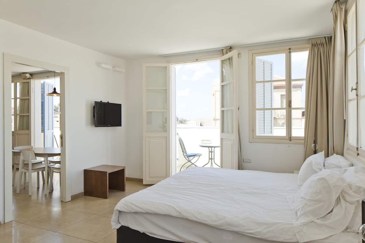 A hotel room with a bed, a TV, a small table, and a chair.
