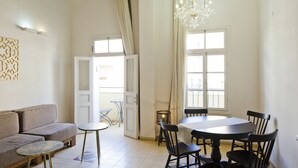 Une pièce avec un canapé, une table à manger et des chaises, un lustre et un vélo en arrière-plan.