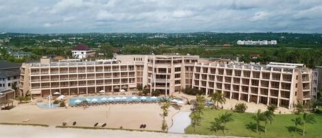 A hotel with multiple floors, a swimming pool, and a beach area.