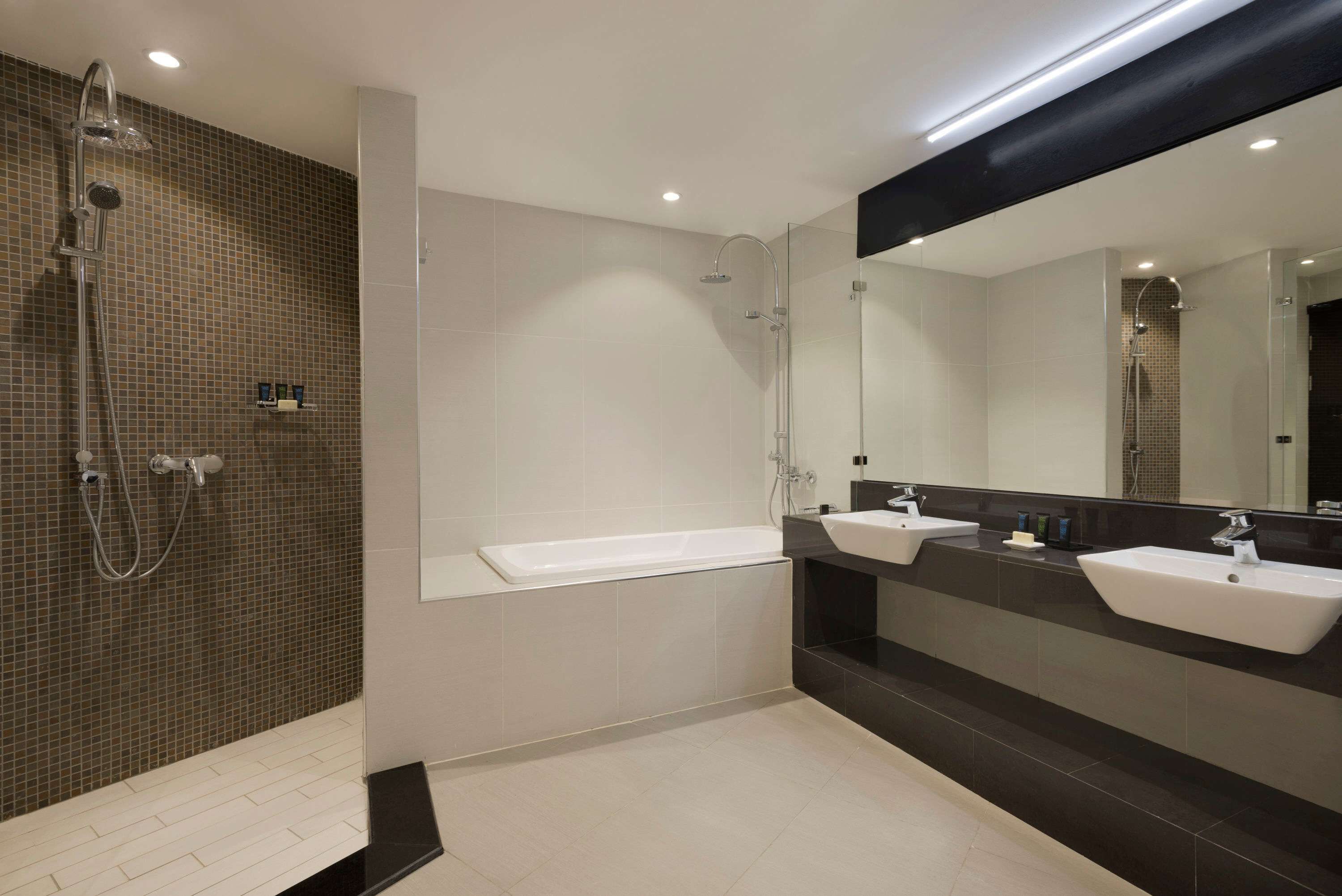 A modern bathroom with a glass-enclosed shower, a standalone bathtub, and two sinks.