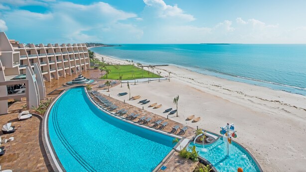 Un resort con piscina, playa y vista al océano.