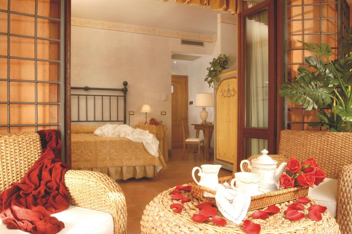 A cozy room with a bed, a sitting area with a table, and a large window with a view.