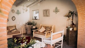 Ein gemütliches Zimmer mit rustikalem Charme, ausgestattet mit einem Holzsofa, einer weißen Bank und einem kleinen Tisch mit einer Pflanze.
