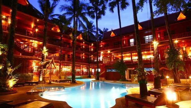 Un hotel con piscina rodeada de sillas de descanso y palmeras.