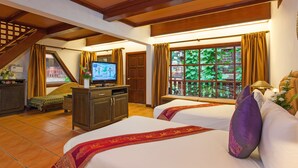Una habitación de hotel con dos camas, una televisión, un escritorio con una computadora y una ventana con cortinas.