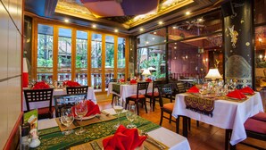 Un restaurante con varias mesas dispuestas para comer, que ofrece vistas a zonas verdes exteriores.