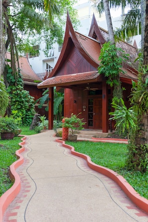A traditional wooden building with a curved pathway leading to the entrance. - Royal Phawadee Village (Patong)