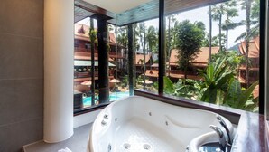 Un baño moderno con una bañera grande, vistas a una piscina y un espacio exterior con edificios y árboles.