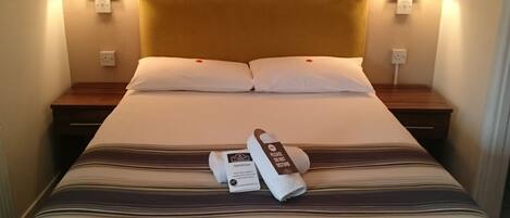 A hotel room with a large bed, two bedside lamps, and a wooden headboard.