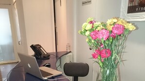 A reception desk with a laptop, a phone, and a vase of flowers. - Livingston Lodge Hotel (Livingston)
