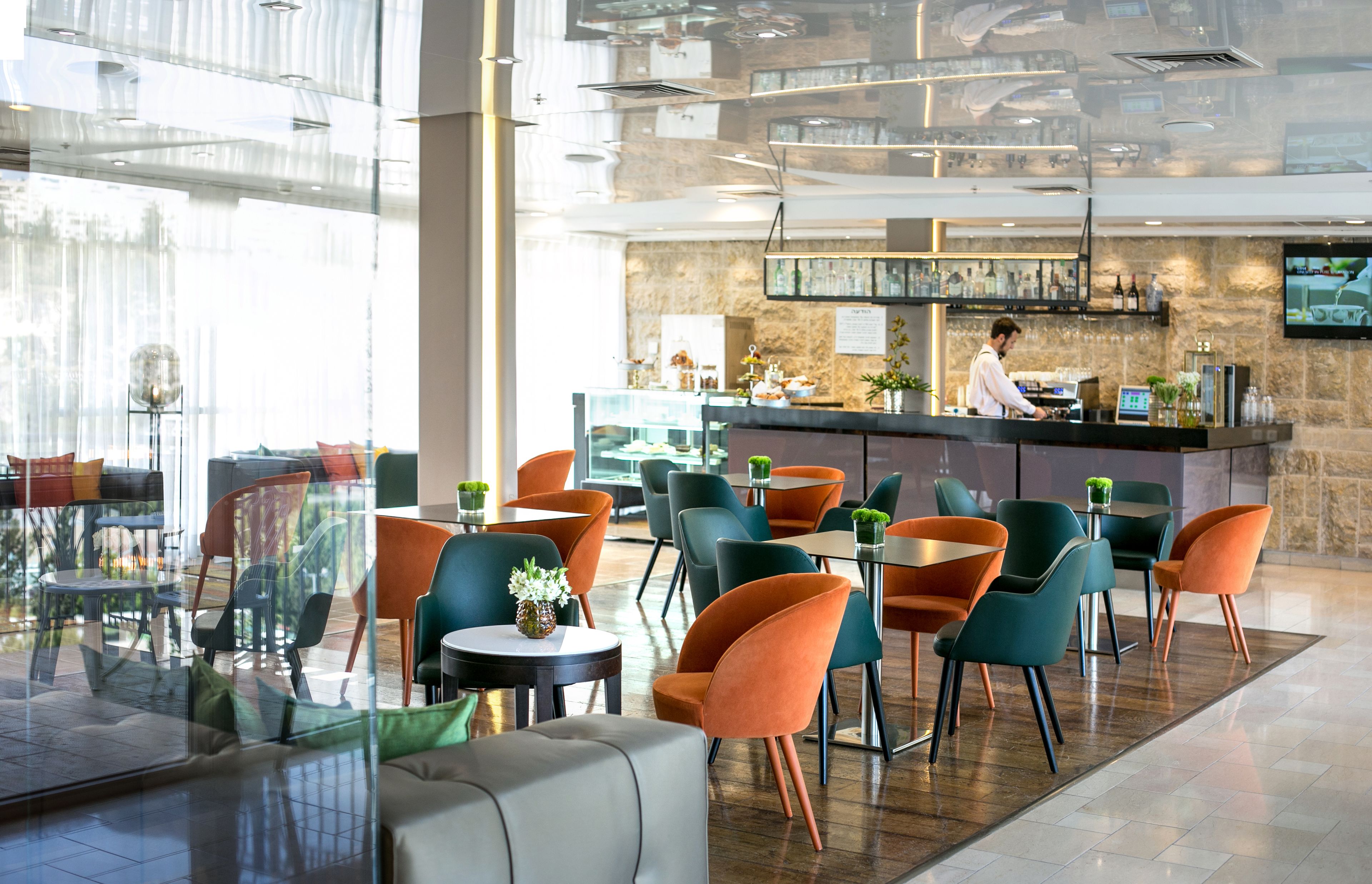 A modern hotel lobby with a bar area, seating arrangements, and a large window providing natural light.