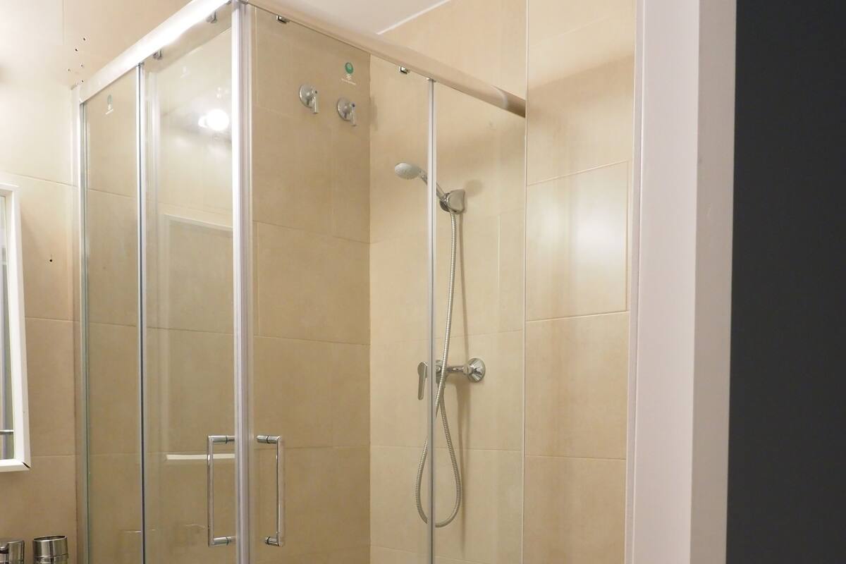 Cabina de ducha con paredes de cristal, un inodoro y un lavabo en un baño.