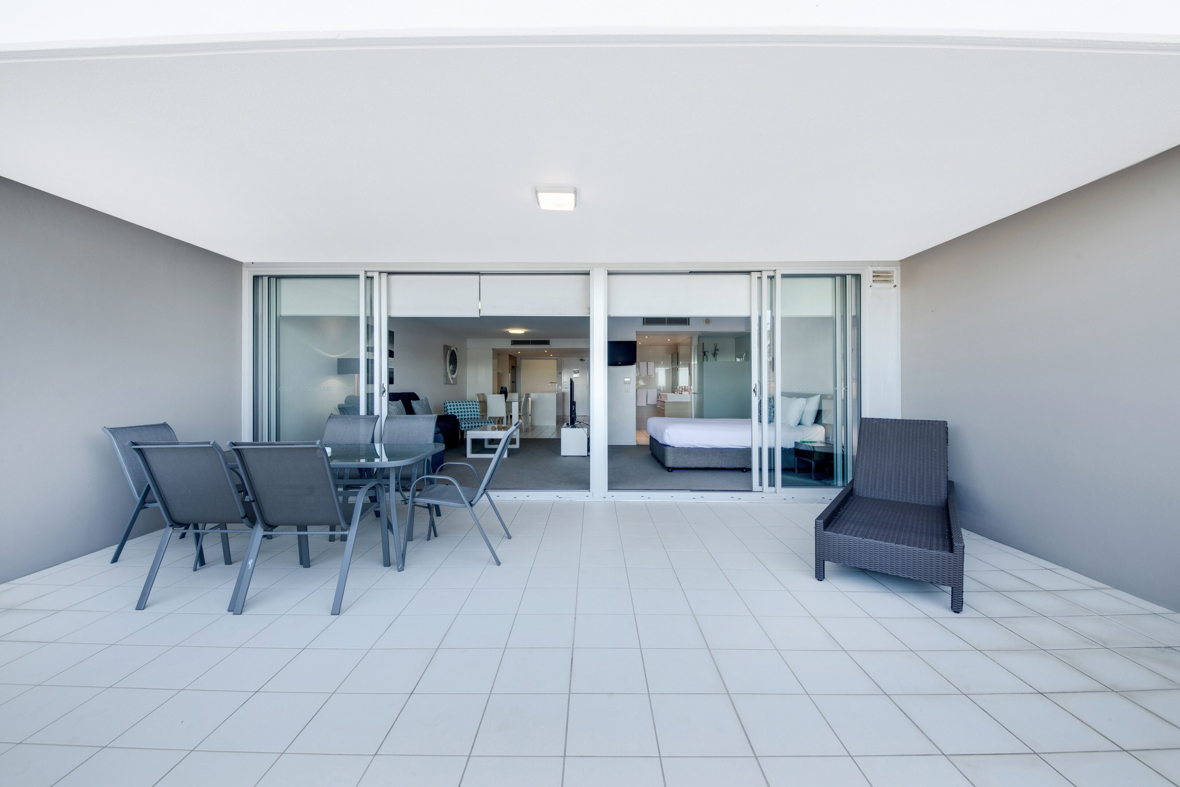 Una habitación de hotel moderna con balcón, una zona de comedor con sillas y una mesa, y una cama.
