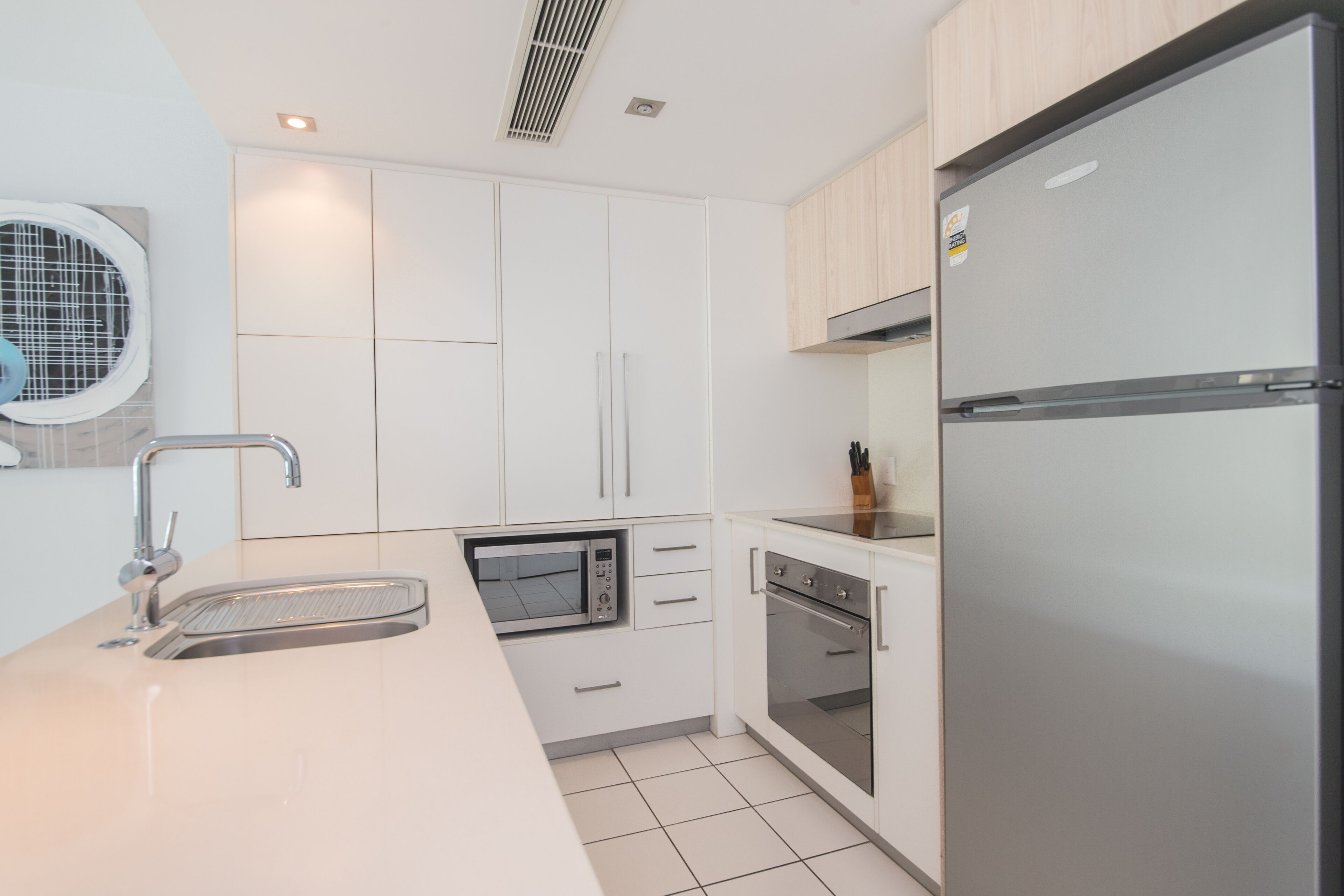 A modern kitchen with white cabinetry, stainless steel appliances, and a built-in oven.
