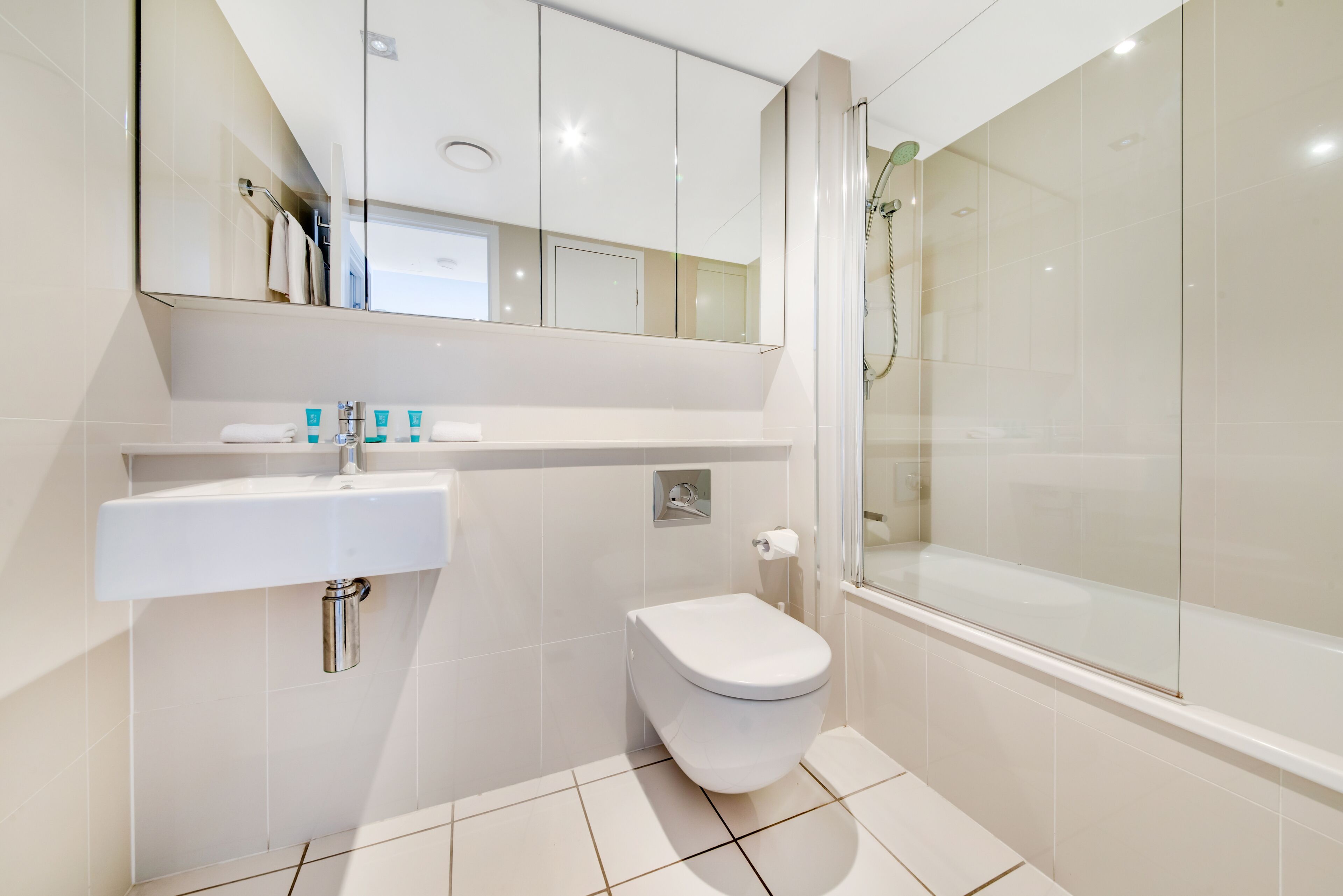 Une salle de bain moderne avec un lavabo, des toilettes et une douche, le tout de couleur blanche.