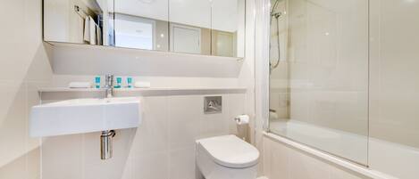 Une salle de bain moderne avec un lavabo, des toilettes et une douche, le tout de couleur blanche.