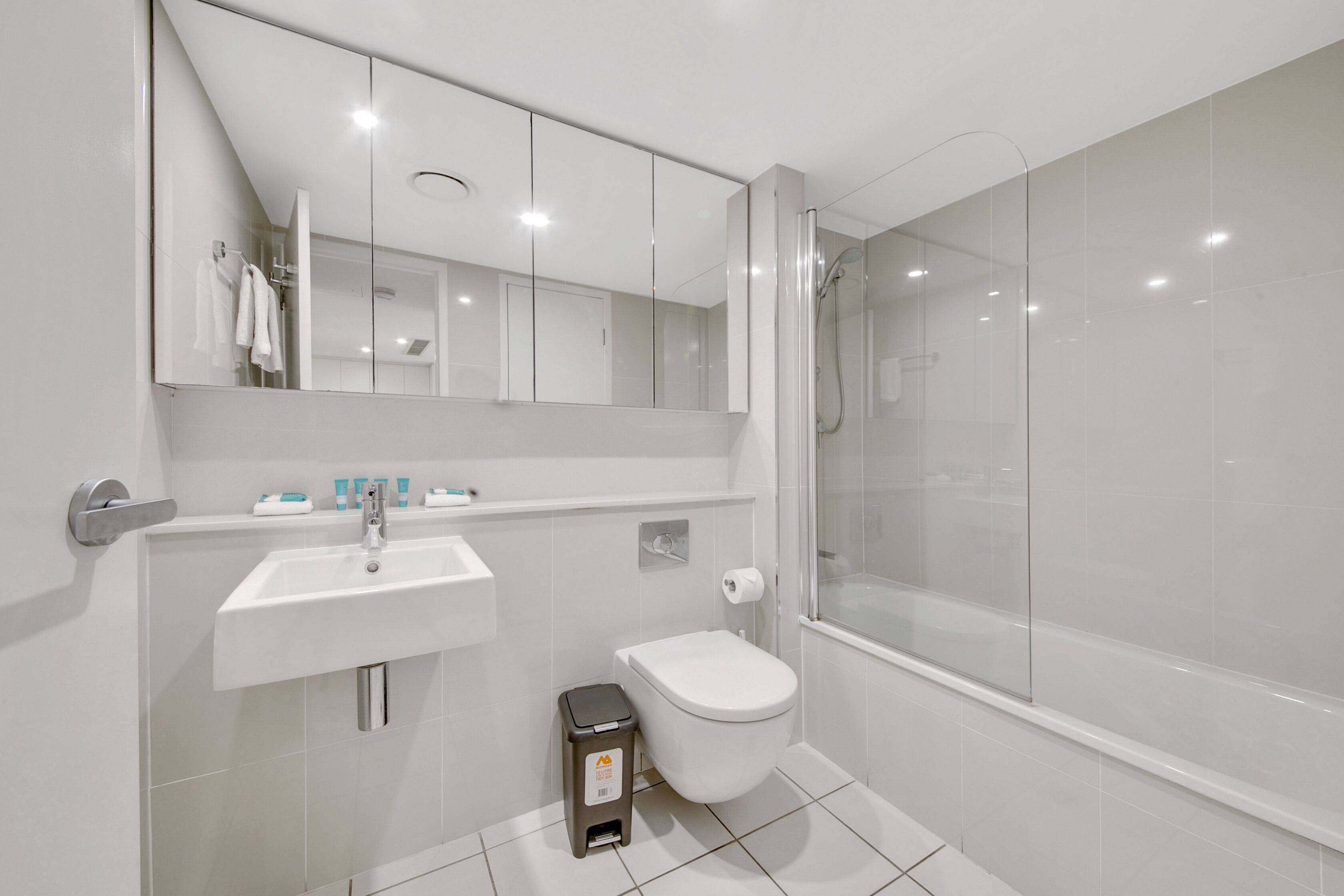 Une salle de bain moderne avec un lavabo blanc, des toilettes et une douche à parois de verre.