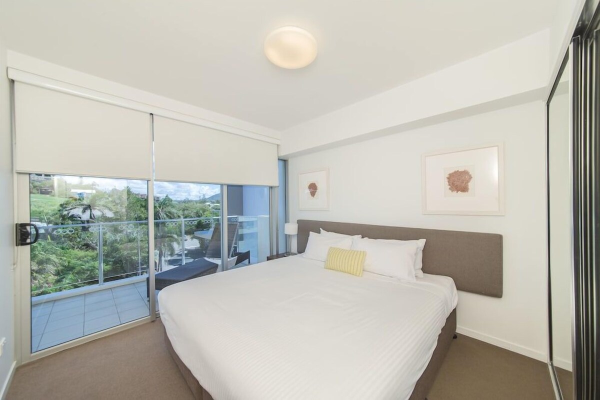A bedroom with a bed, a window, and a balcony.