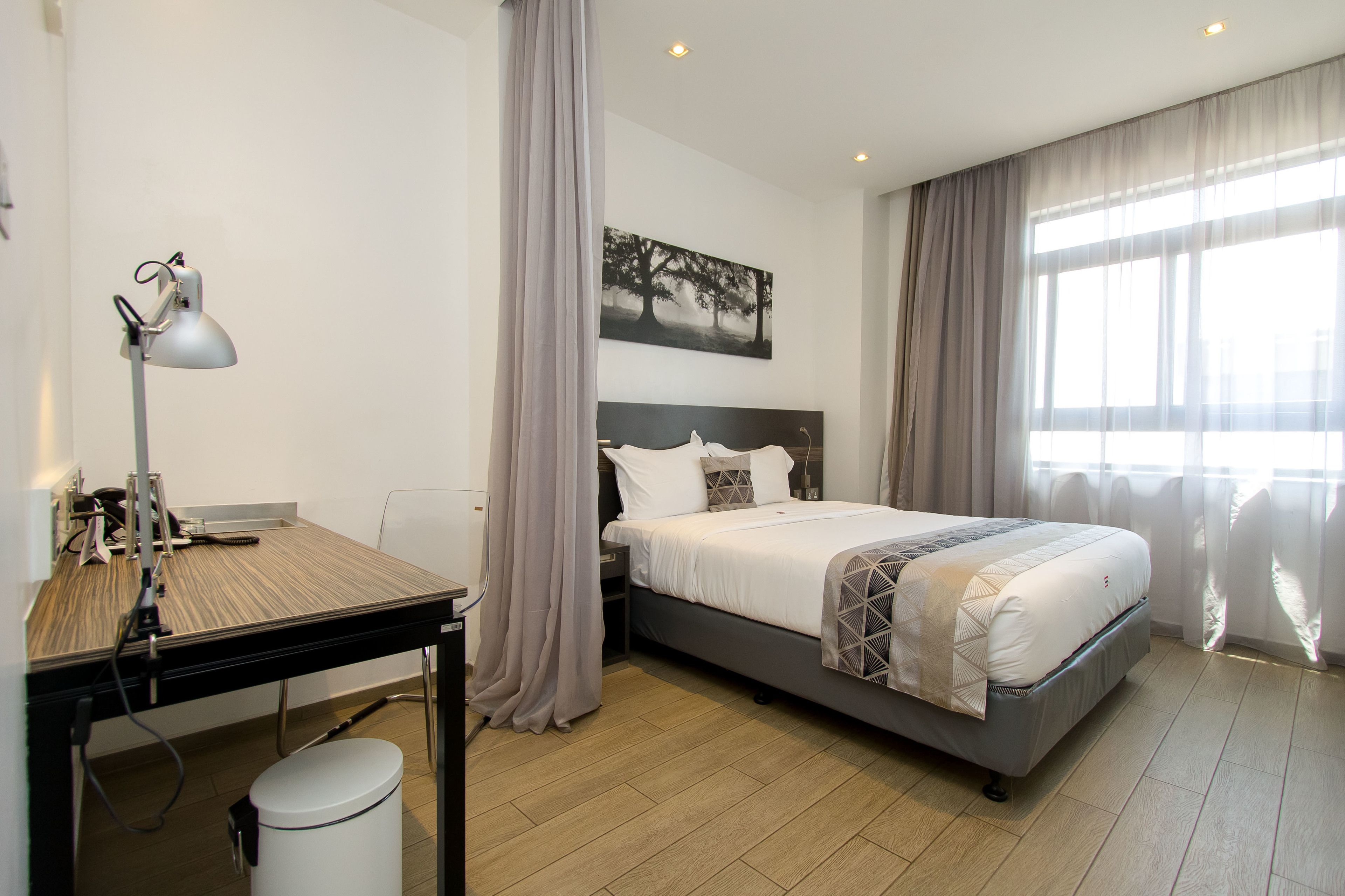 Ett modernt hotellrum med en säng, ett skrivbord och en dator.