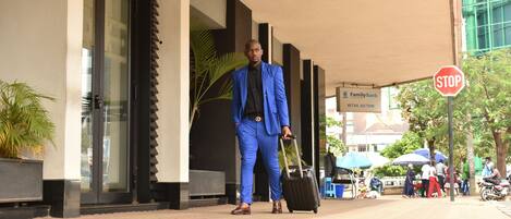 Un hombre con traje azul y una maleta, de pie frente a un edificio con un letrero que dice 'FamilyBank'.