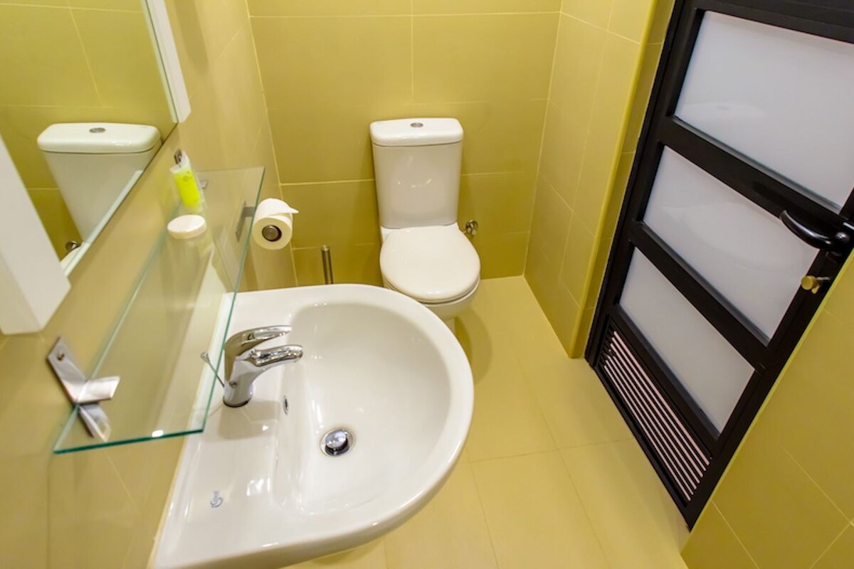 A bathroom with a white sink, a toilet, and a glass shower enclosure.
