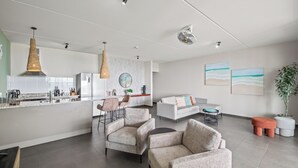 Un espace de vie moderne comprenant une cuisine, deux canapés, un coin repas et une grande plante en pot.