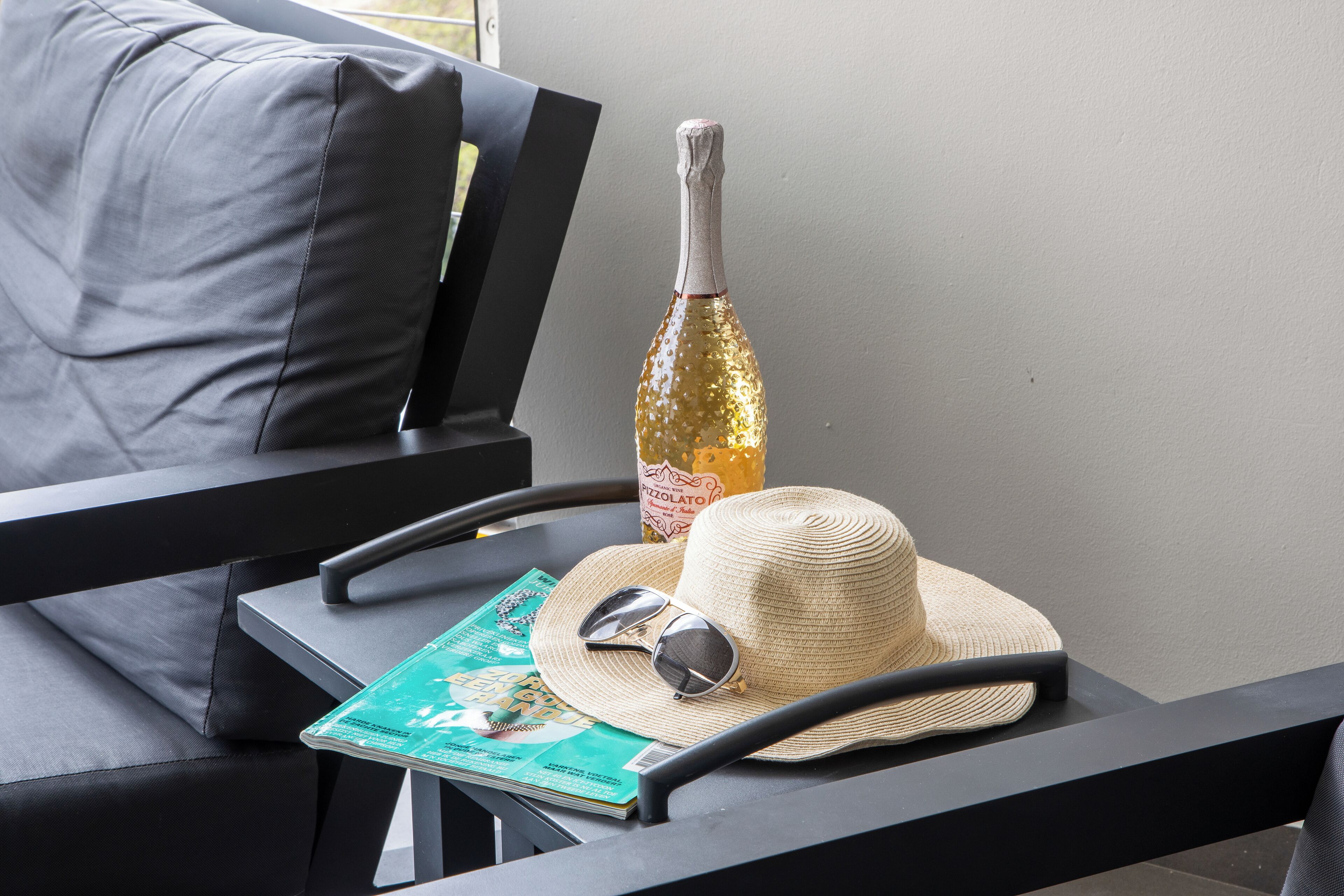 A magazine, a straw hat, and a bottle on a table.