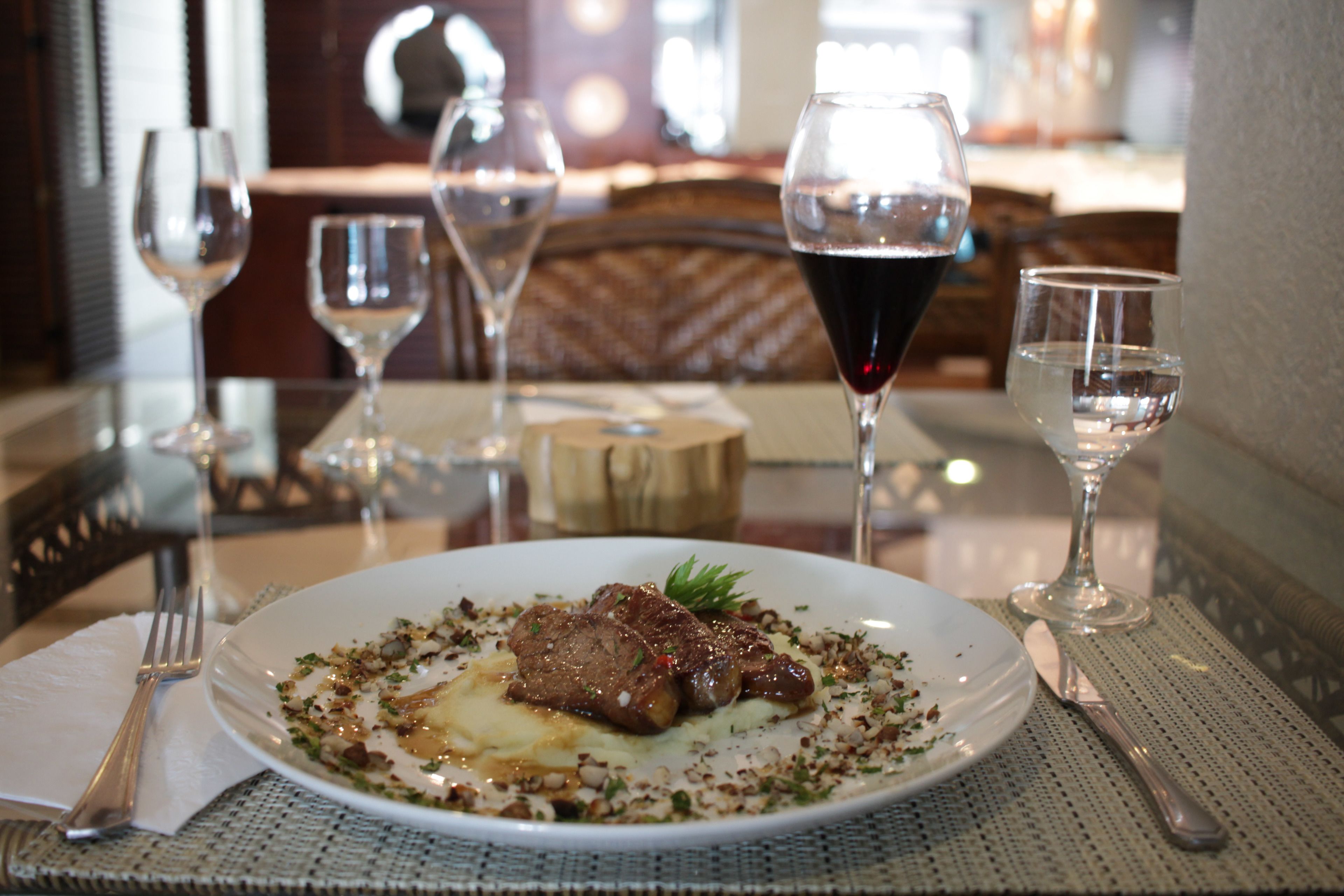 A dining table with a plate of food, wine glasses, and cutlery.