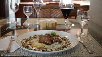 A dining table with a plate of food, wine glasses, and cutlery.