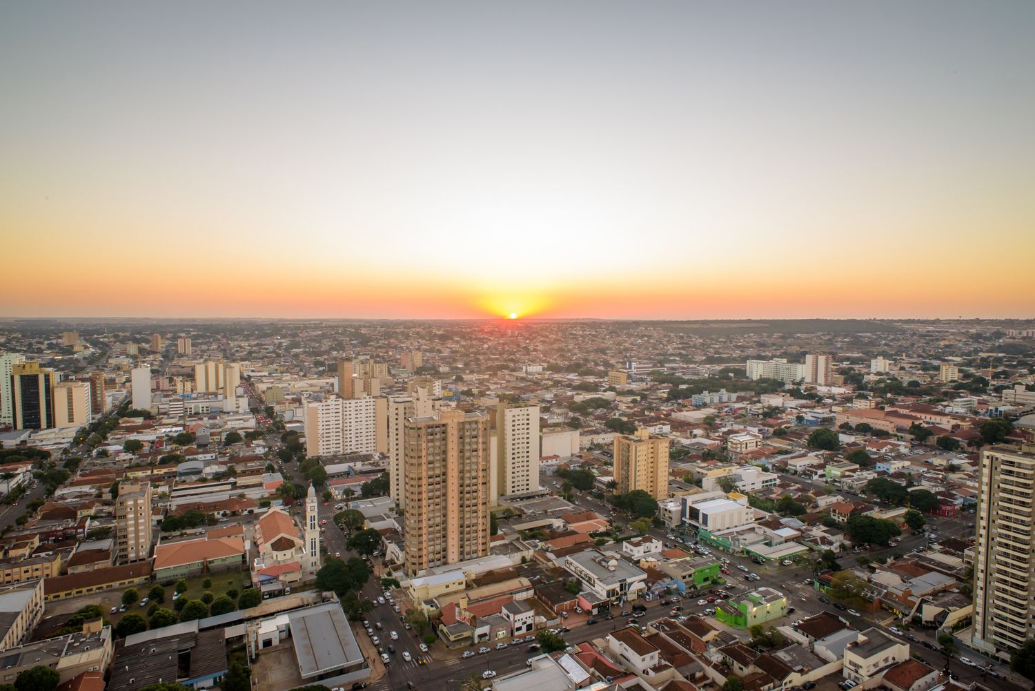 Un paisaje urbano con rascacielos, una iglesia destacada y una vista despejada del atardecer.