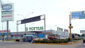Una tienda TOTTUS con un letrero grande, un paso de peatones y un semáforo.
