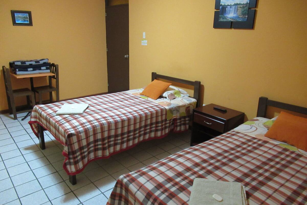 Une chambre d’hôtel avec deux lits, un bureau et une chaise.