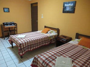 A hotel room with two beds, a desk, and a chair. - Kurmi Hostel Lima Airport (Callao)