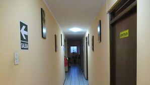 Un pasillo con un cartel que indica la dirección de salida, un extintor y una puerta con la etiqueta 'ADMINISTRACION'.