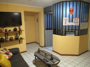 A hotel lobby with a reception desk, a television, and a sofa. - Kurmi Hostel Lima Airport (Callao)