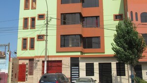 Un edificio de varios pisos con techo plano, varias ventanas y una puerta de garaje visible.