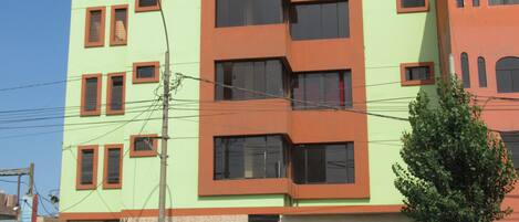 Un edificio de varios pisos con techo plano, varias ventanas y una puerta de garaje visible.