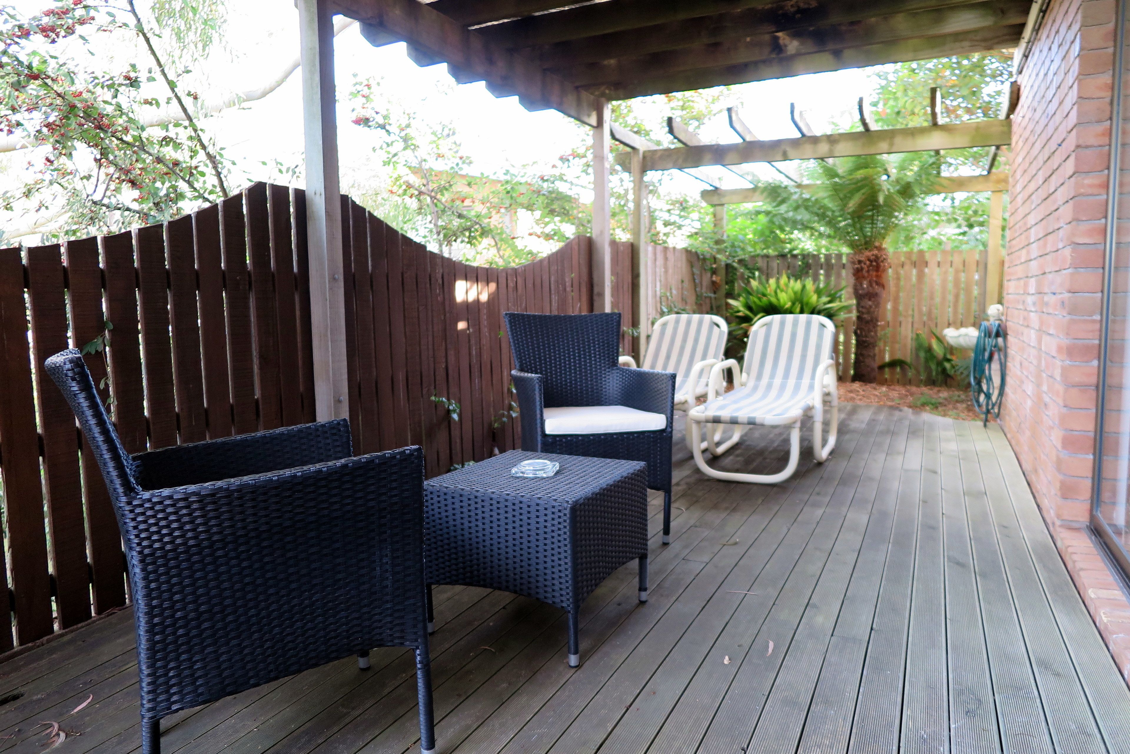 A covered patio with wicker furniture and a brick wall.