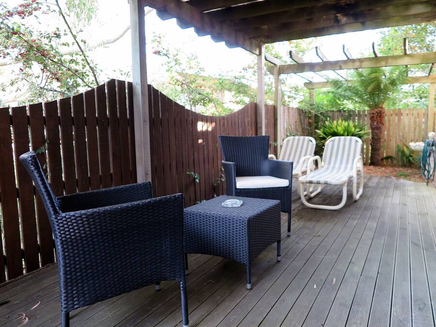A covered patio with wicker furniture and a brick wall.