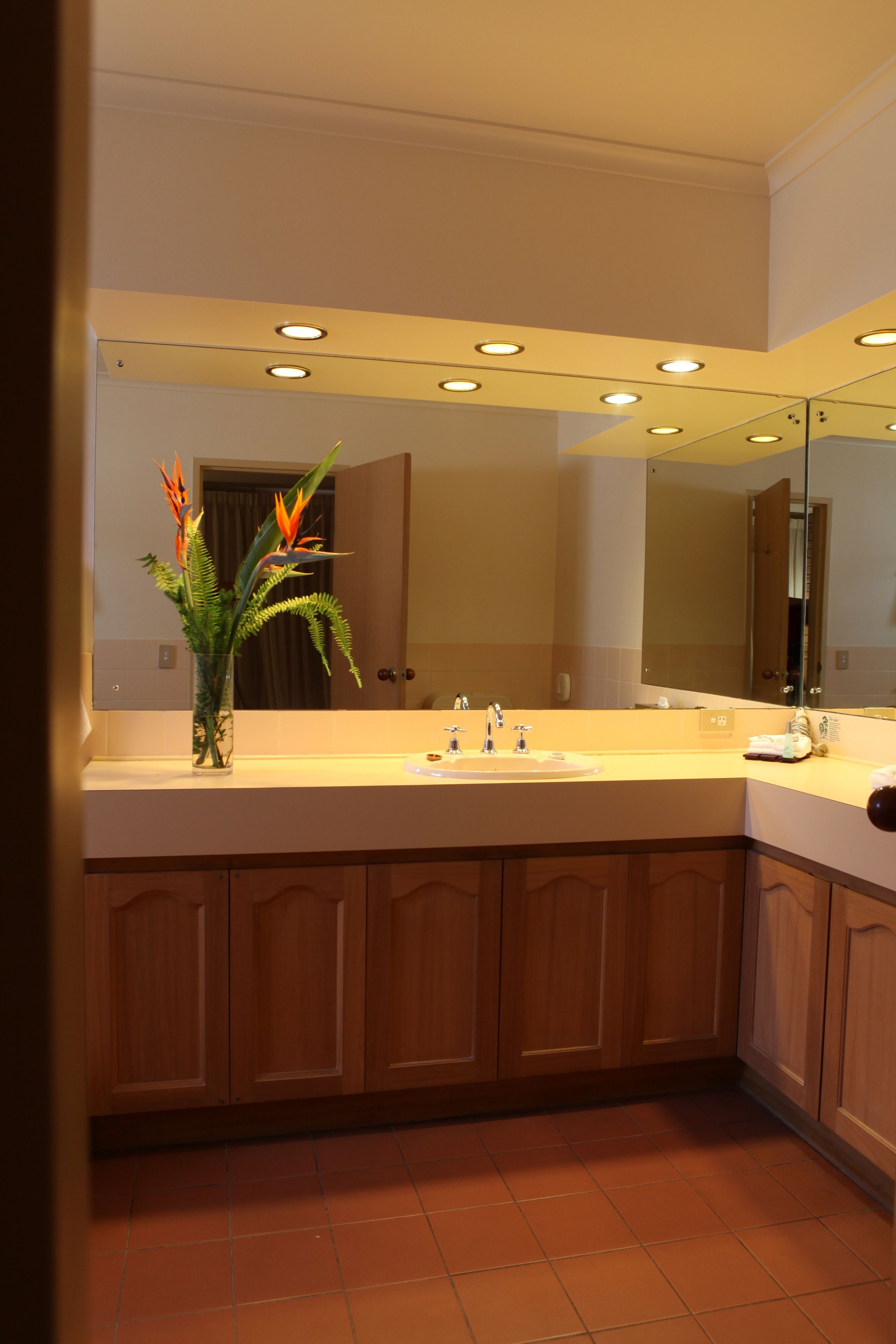 Un bagno moderno con uno specchio grande, un lavabo e mobili in legno.