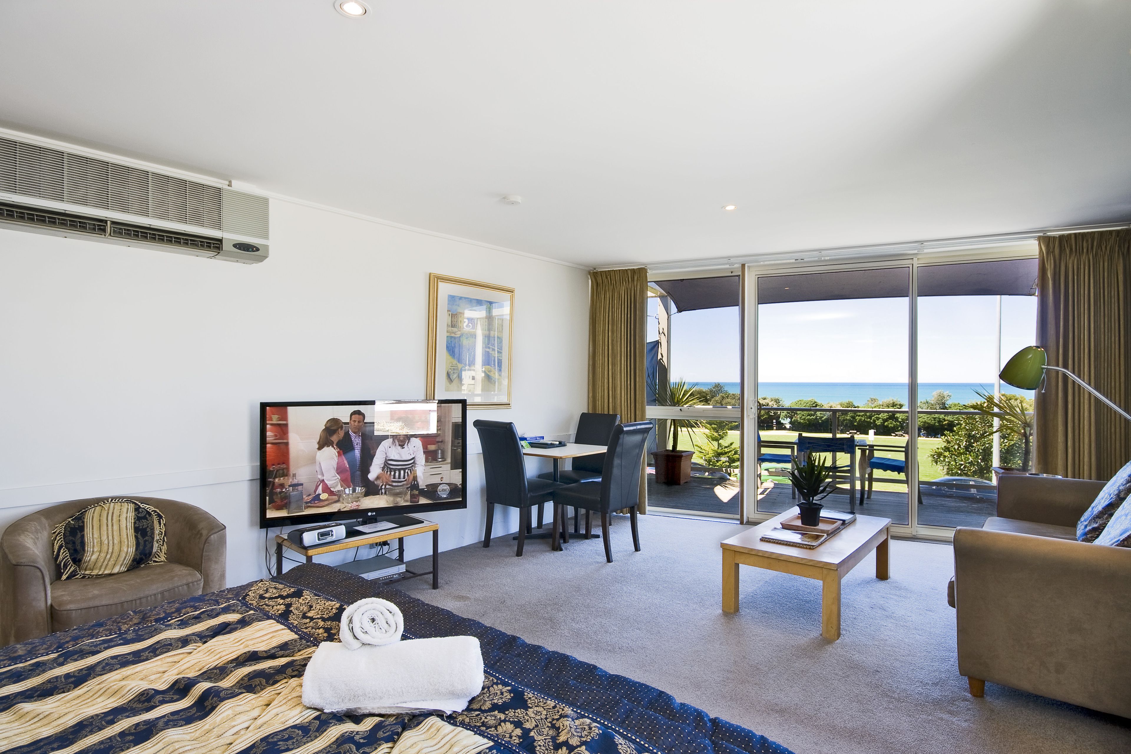 Una habitación de hotel con cama, televisión, escritorio y balcón con vistas.