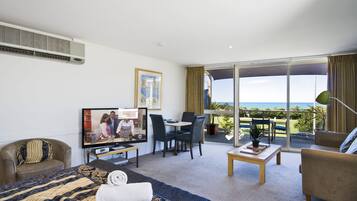 Una habitación de hotel con cama, televisión, escritorio y balcón con vistas.