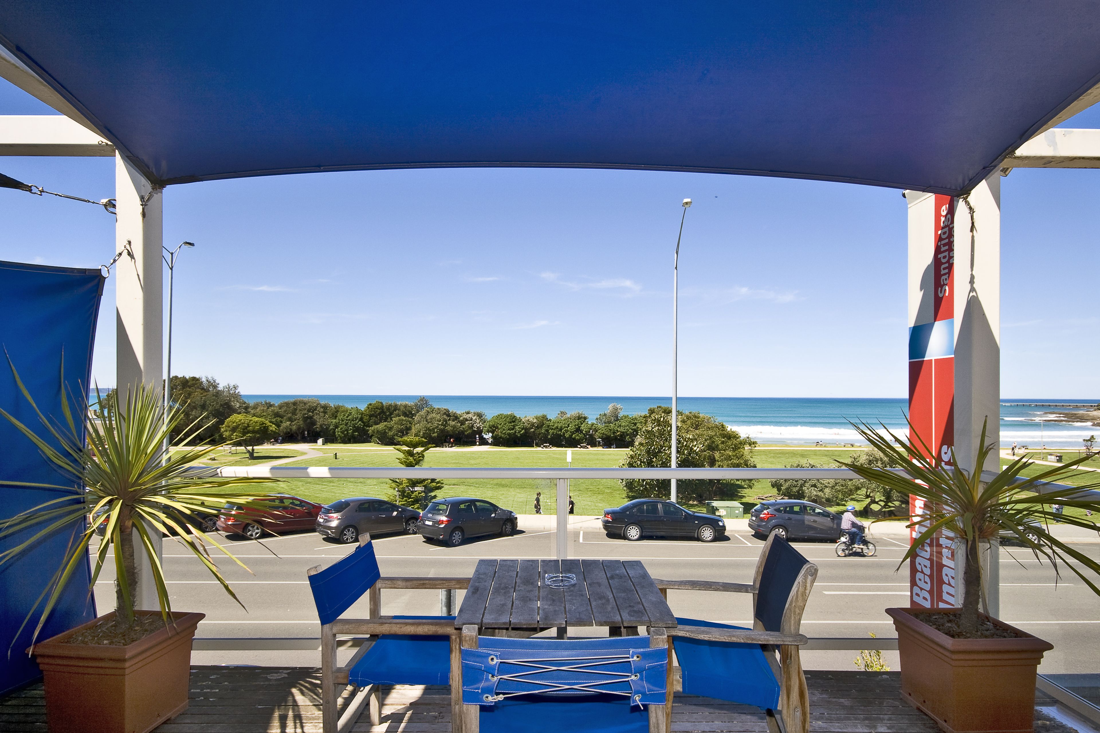 A covered outdoor seating area with a view of the beach and ocean.