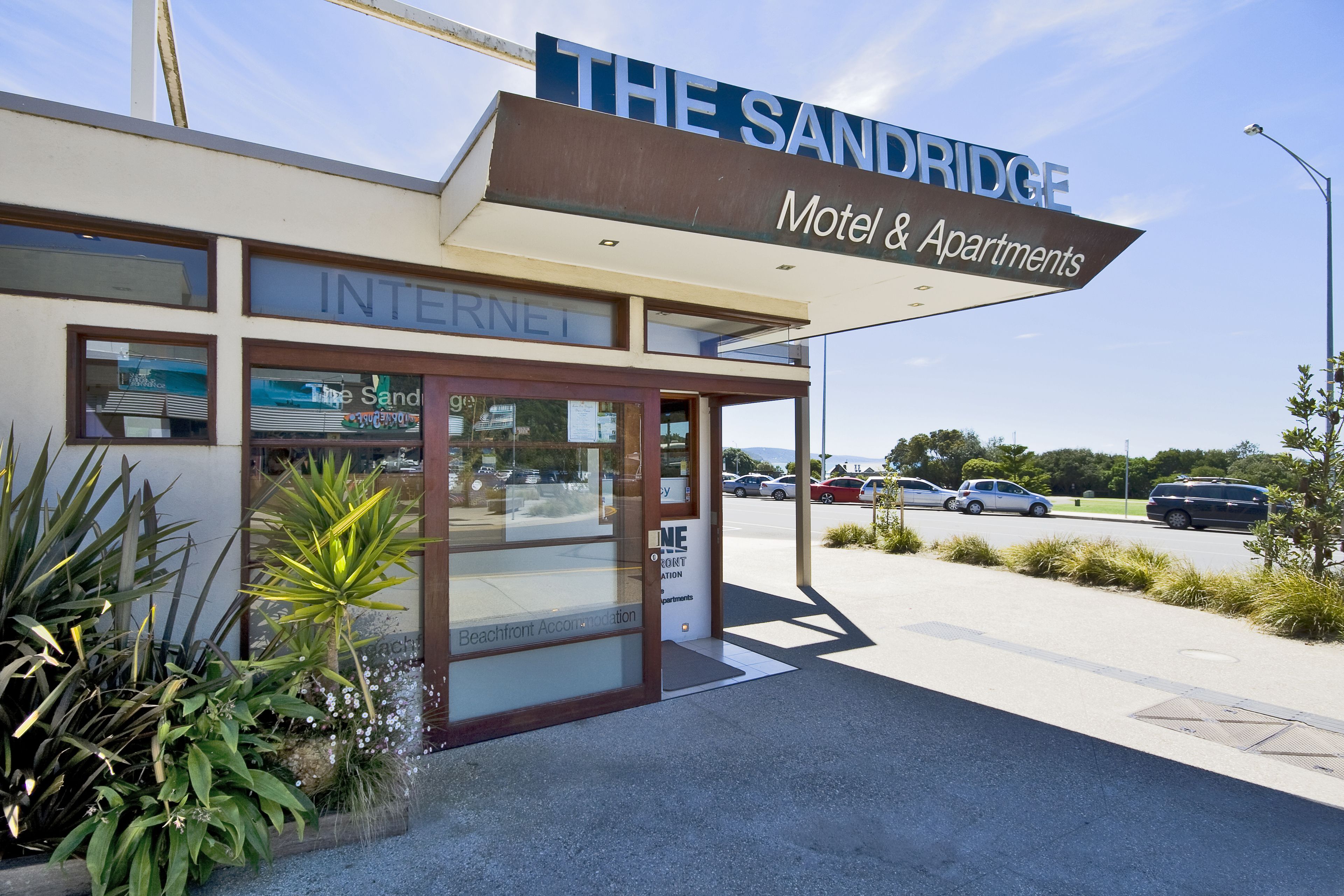 The Sandridge Motel & Apartments with a clear entrance, visible signage, and a landscaped area with plants.