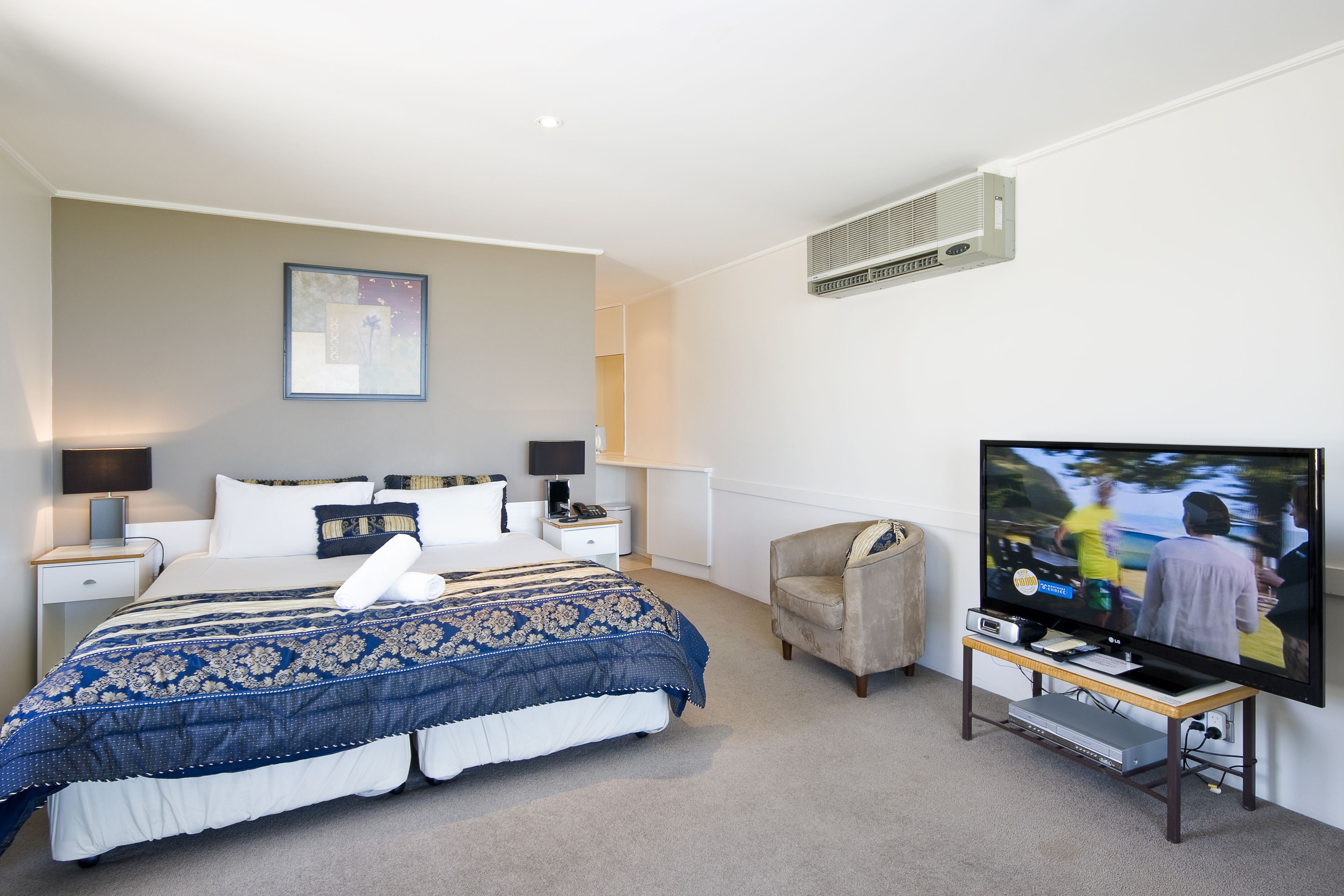 A hotel room with a large bed, a television, a chair, and a desk.