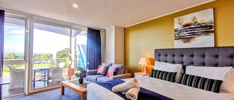 A hotel room with a bed, a sofa, a table, and a balcony with a view.