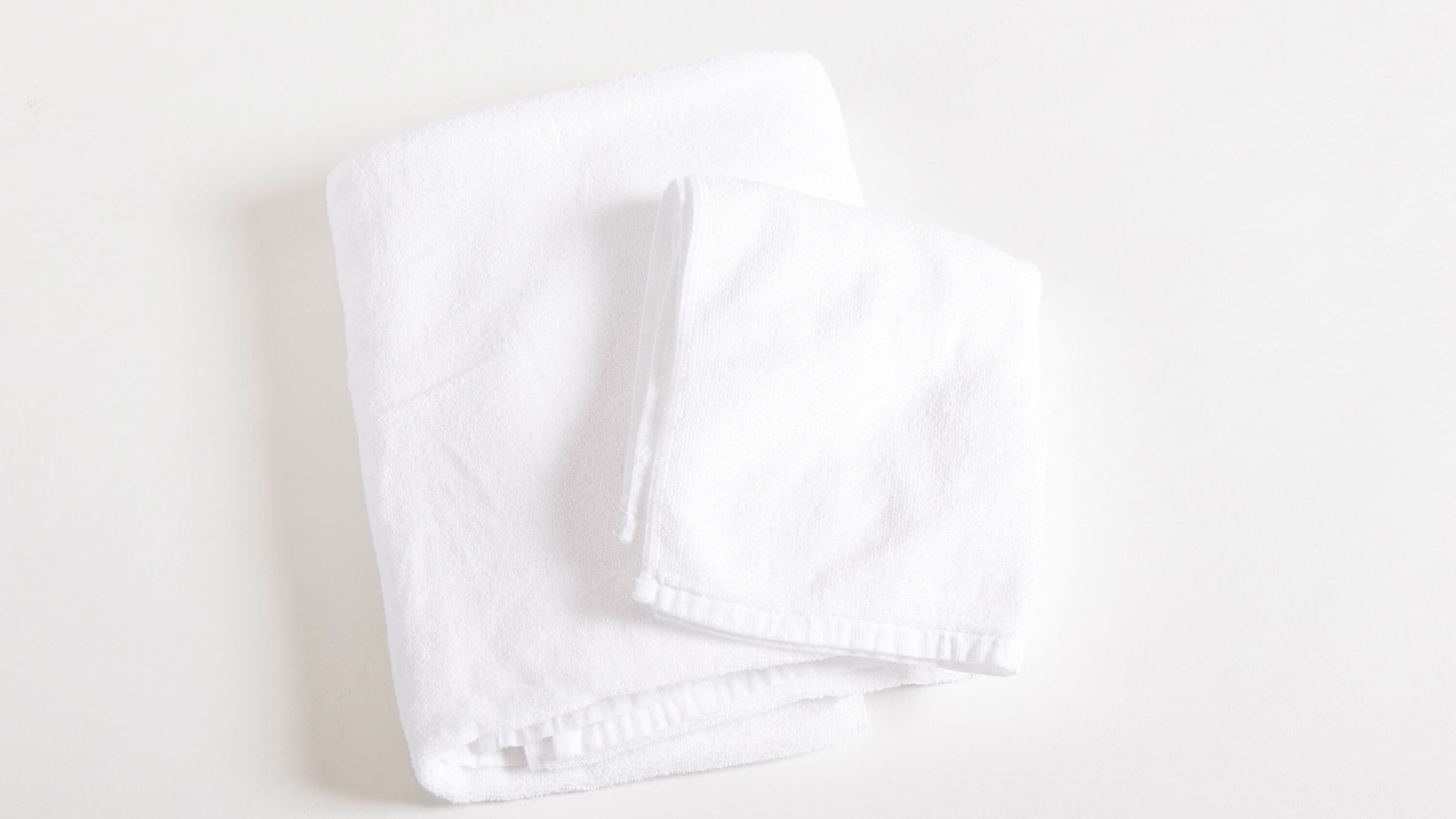 A neatly folded white towel on a plain white background.