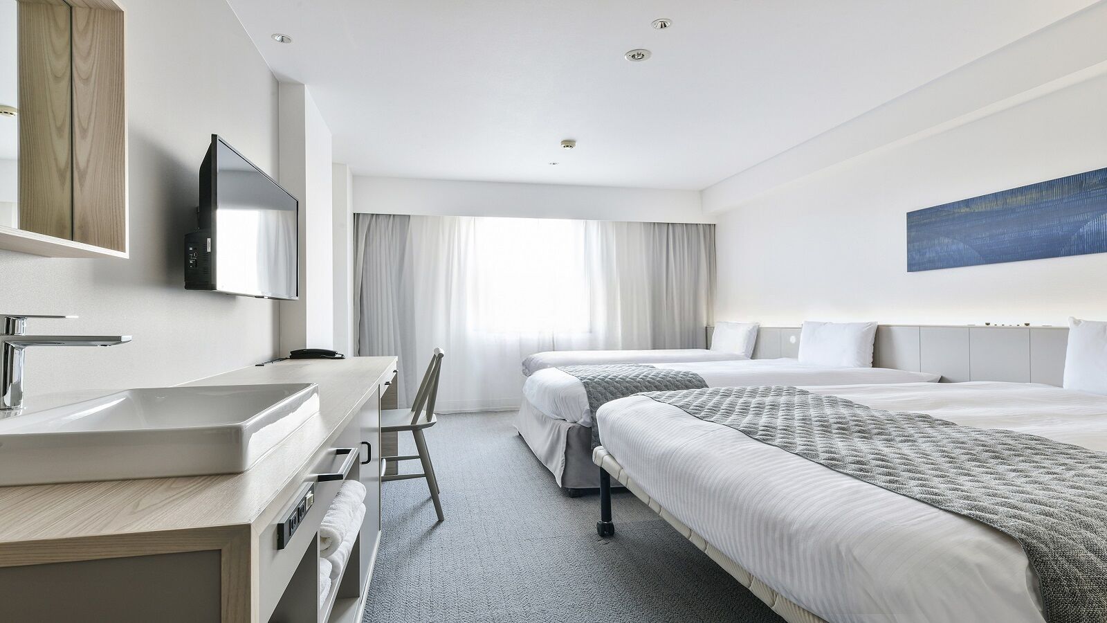 Ein Hotelzimmer mit Schreibtisch, zwei Betten, einem Fernseher und einem großen Fenster mit Vorhängen.