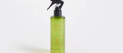 A green spray bottle with measurement markings and text, likely a cleaning product.